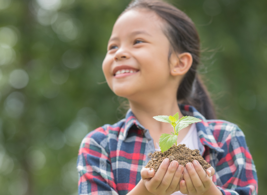 Kind mit fruchtbarem Boden und Pflanze in der Hand